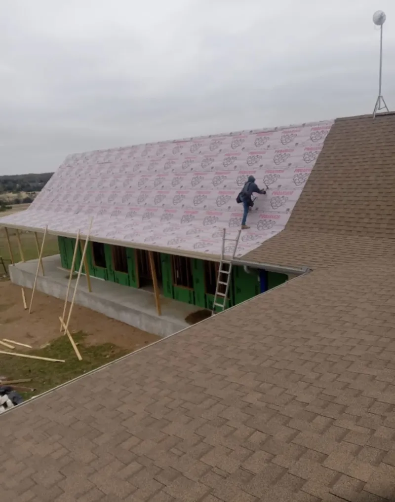Worker preparing underlayment for a metal roof installation in Quartz Hill